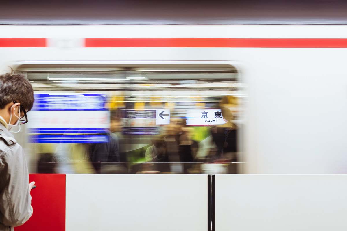 tokyo station A blurry shot of a moving train in front of a man at the Tokyo Station. train